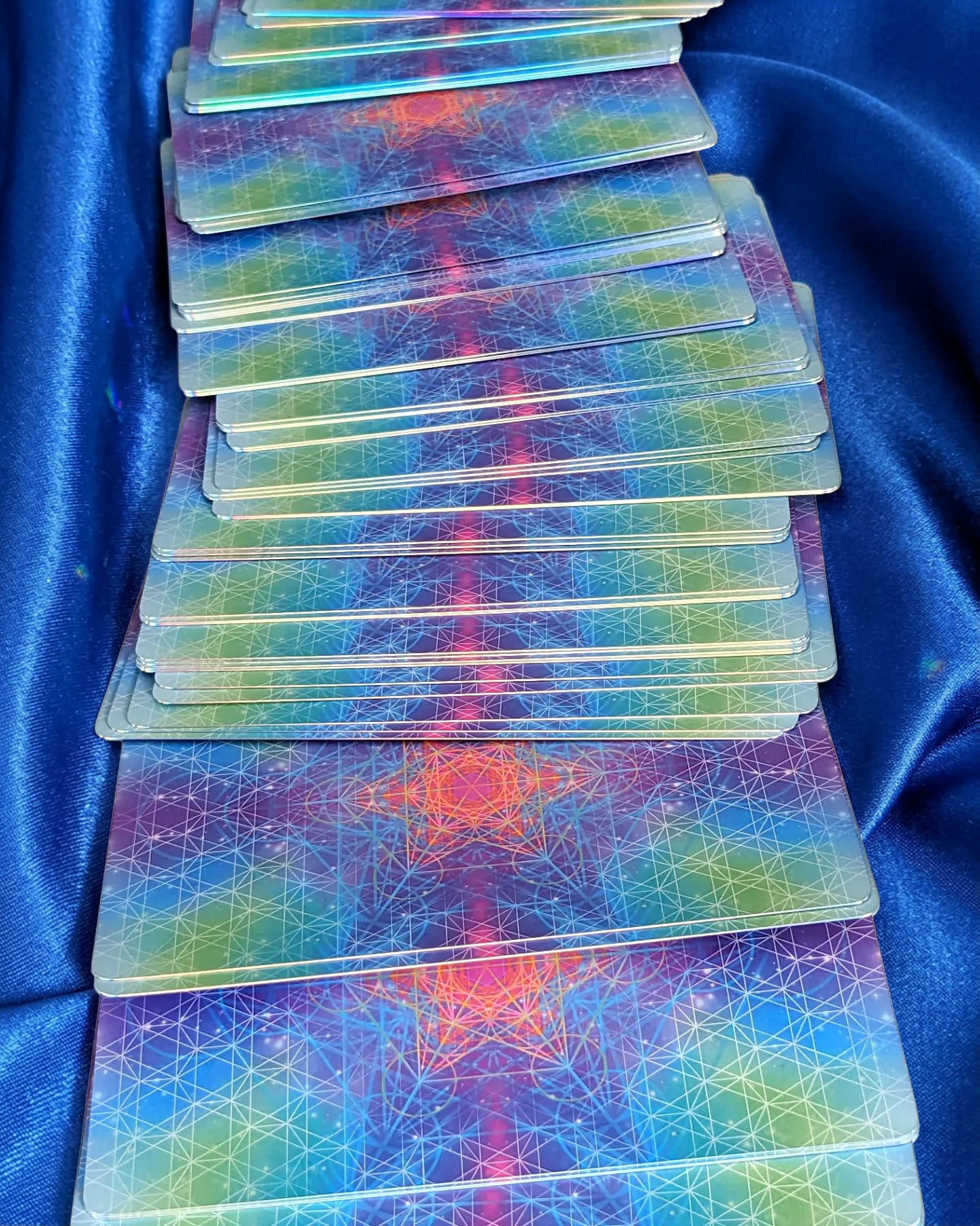 Kaleidoscopic tarot card backs fanned on blue silk